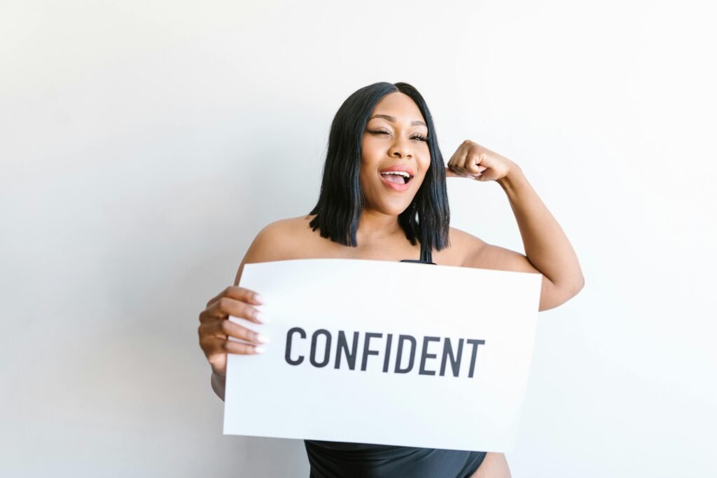 Portrait of a confident pregnant woman holding a sign promoting body positivity and self-love.