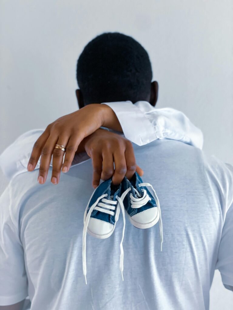 Back view of expectant parents holding baby shoes, symbolizing new beginnings.