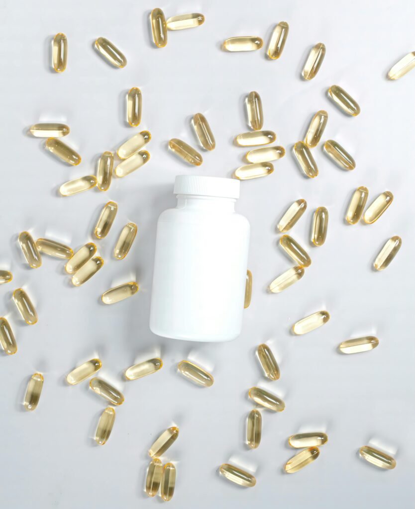 A flat lay of a supplement bottle surrounded by oil capsules on a white surface.