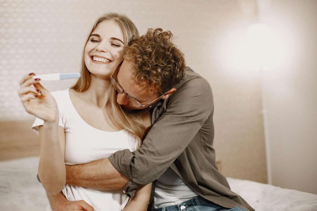 Joyful couple embracing with a positive pregnancy test, celebrating indoors.